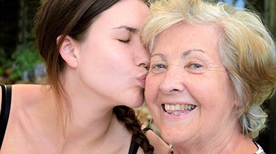 Eine junge Frau küsst eine ältere Frau auf die Wange