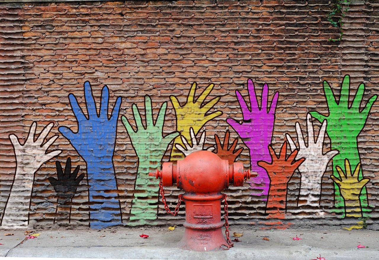 Auf eine Wand sind viel große bunte Hände gemalt
