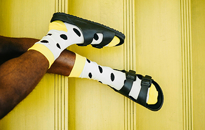 Beine tragen poppige Socken in weiß, gelb, schwarz, schwarze Birkenstock auf gelber Treppe